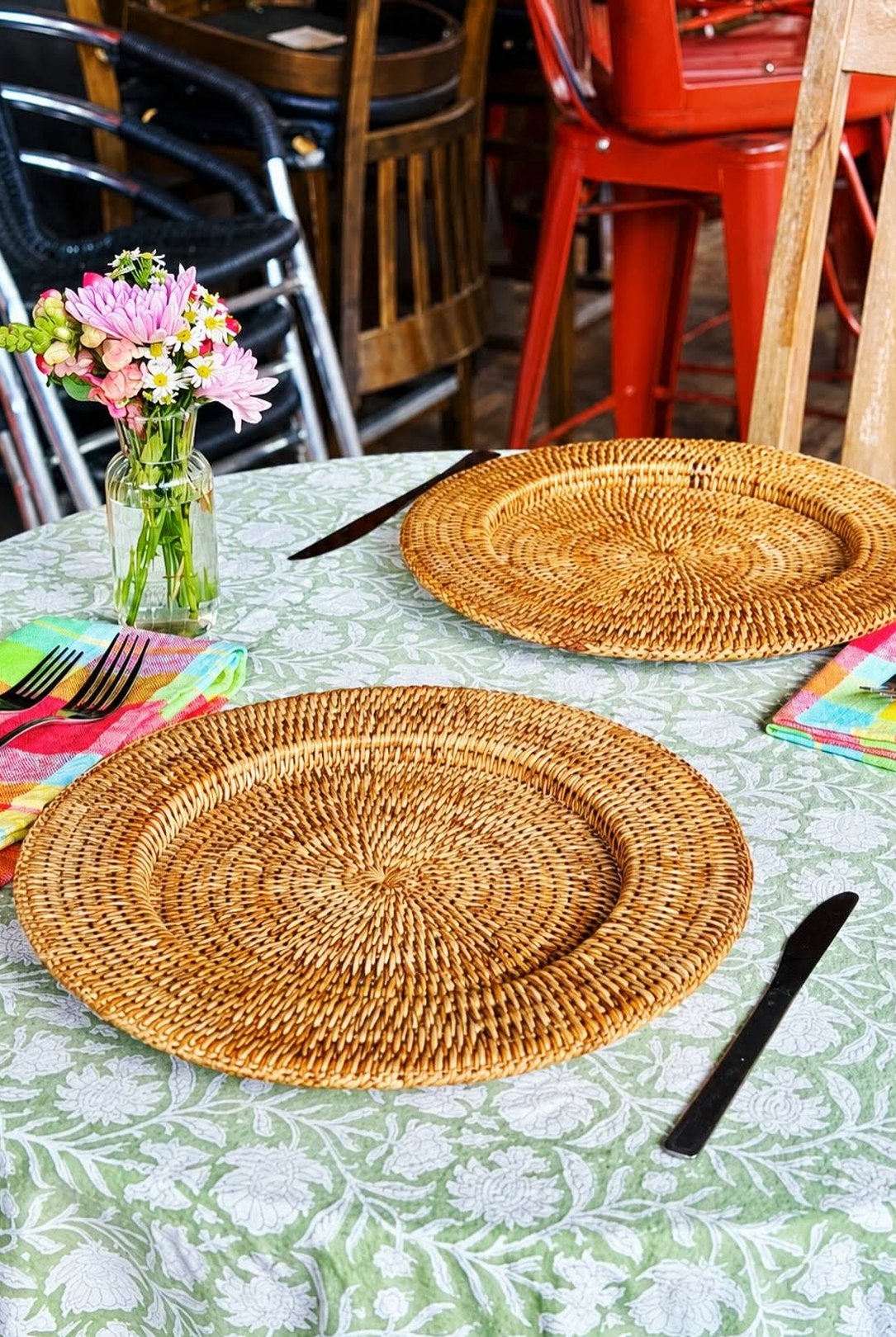 A table in Lou Lou's dining room: sage block-print cloth, rattan chargers, madras napkins and red chairs